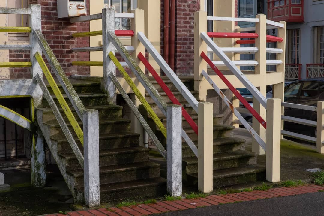 A vibrant weathered concrete staircase with colorful railing outdoors.