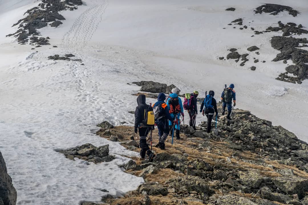 Adventurous group hiking on a snowy mountain ridge during winter, showcasing teamwork.