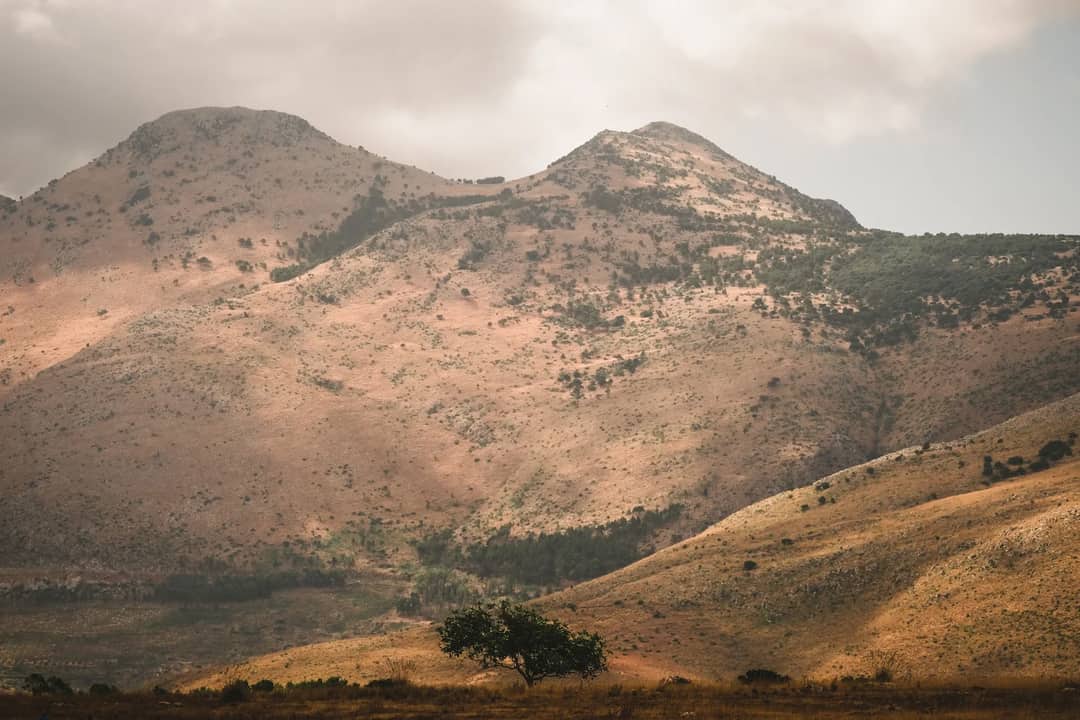 Serene mountain landscape with rolling hills under a cloudy sky.