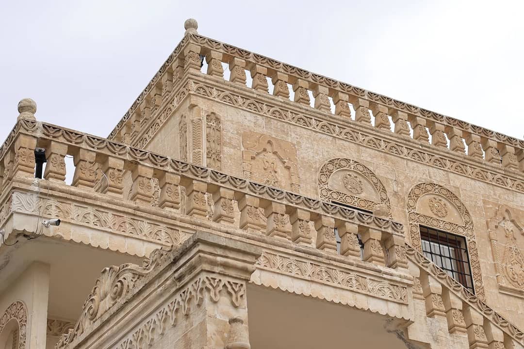 A detailed view of an ornate stone building featuring intricate carvings and railing designs.