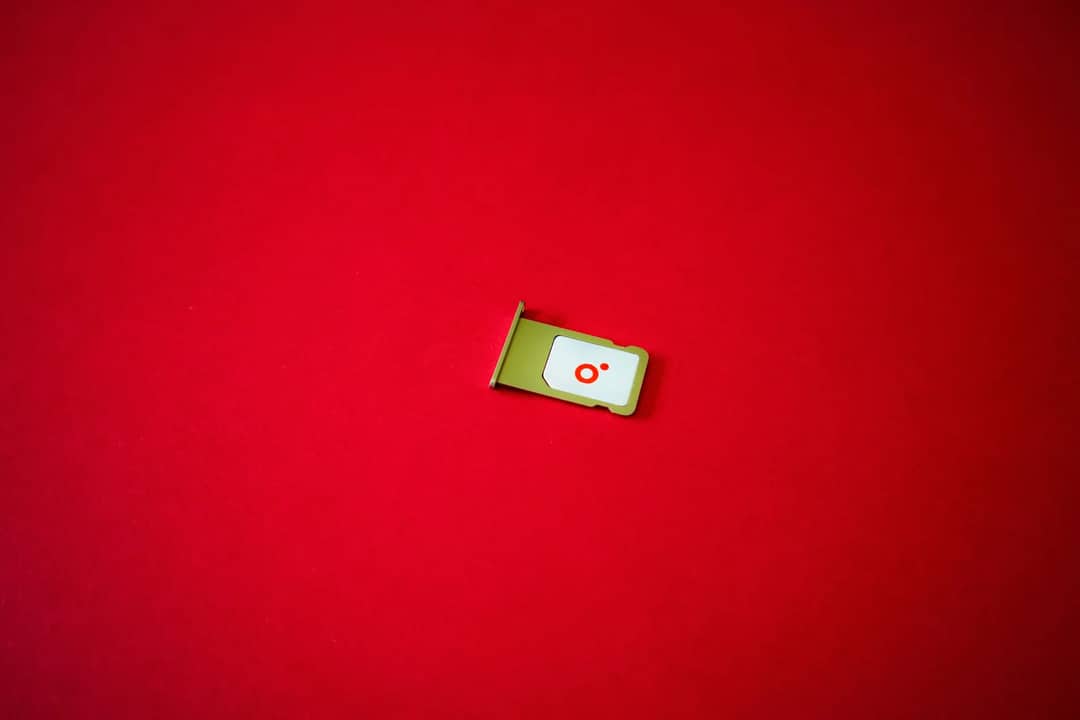 A clean image of a SIM card tray displayed on a vibrant red background.