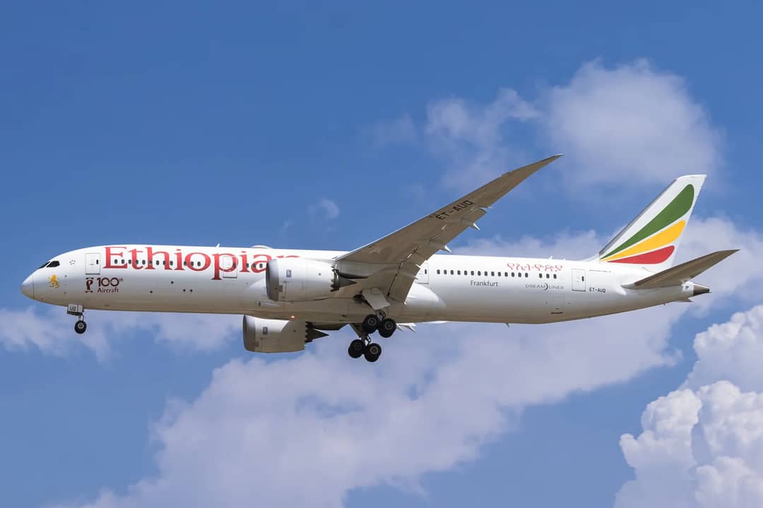 Side view of Ethiopian Airlines Boeing 787 flying against a blue sky with clouds.