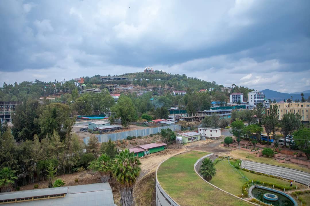 Captivating aerial view of Gondar, Ethiopia with lush greenery and architecture under a cloudy sky.