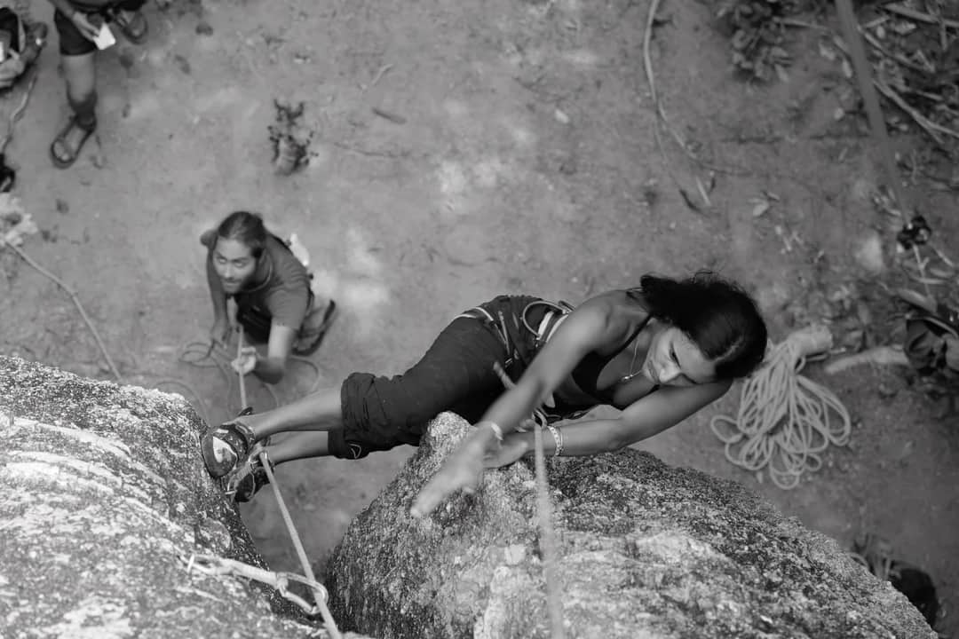 Adventure rock climbing scene in Ko Tao, Thailand featuring a woman ascending a cliff.
