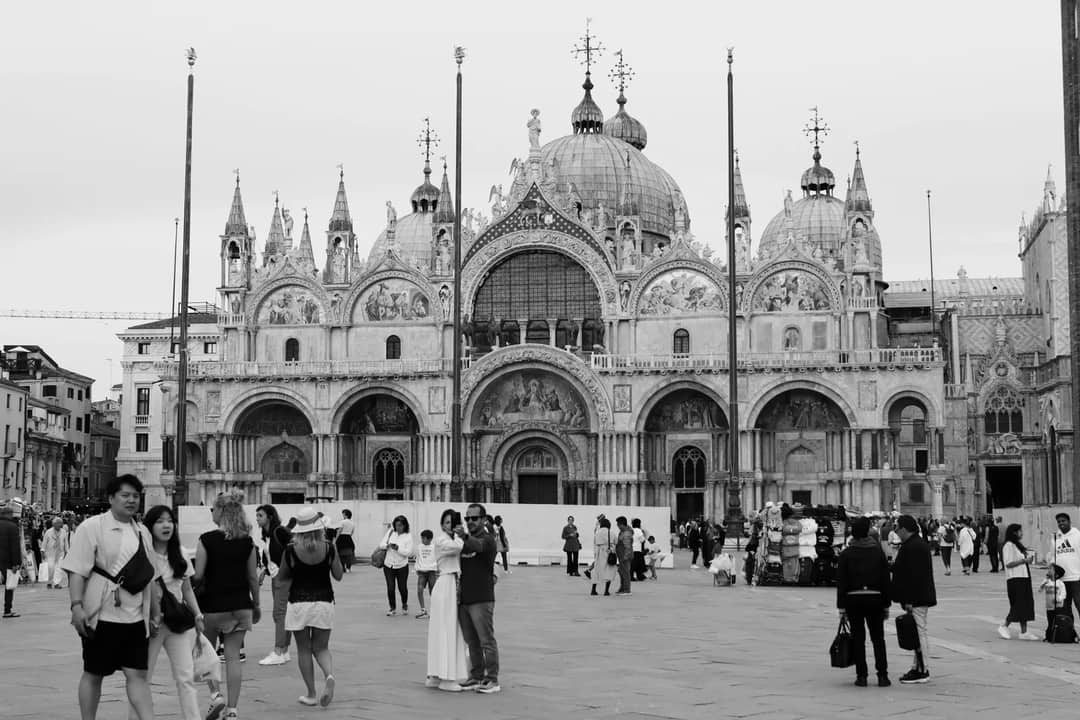 Black and white photo capturing the vibrant crowd at Piazza San Marco in Venice.
