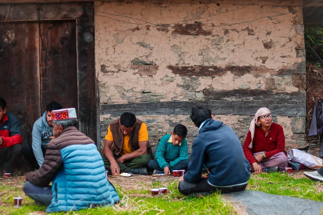 A group of people seated outdoors, engaged in a communal activity.