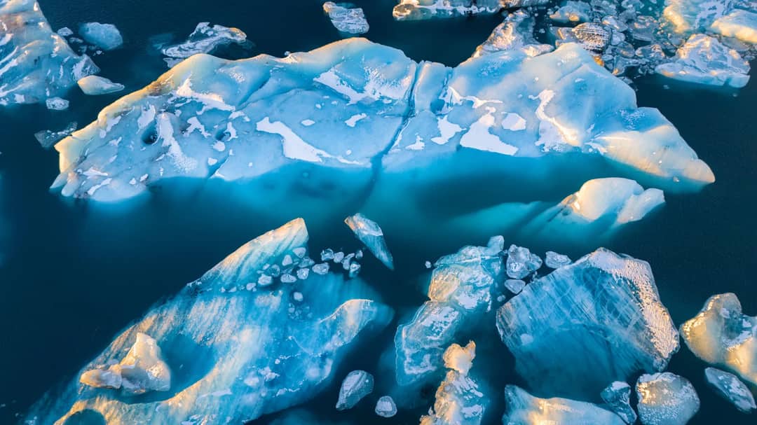 Stunning aerial view of large icebergs floating in deep blue waters.
