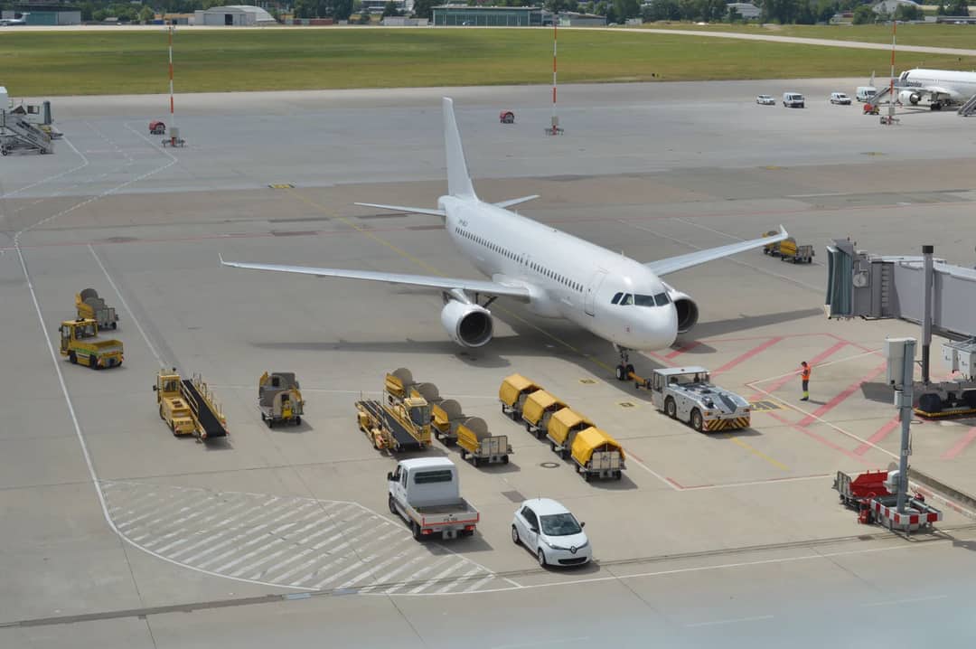 High angle view of a commercial airplane on airport tarmac with ground support vehicles.