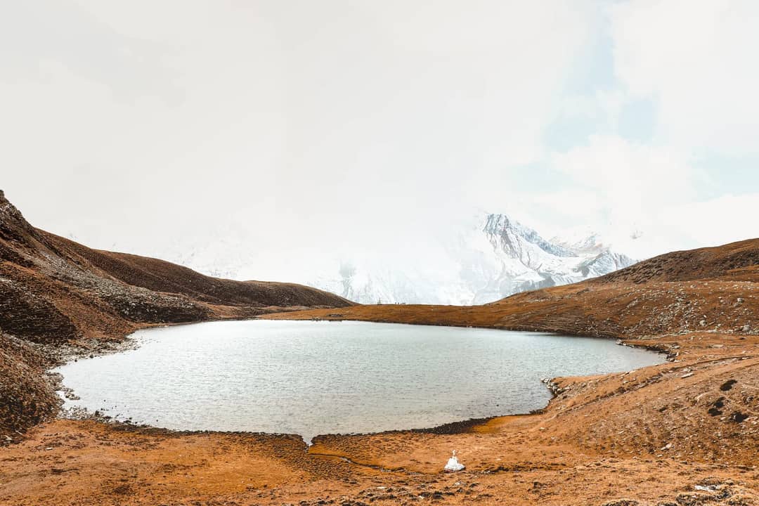 Tranquil alpine lake surrounded by rugged landscapes in Bhraka, Nepal.