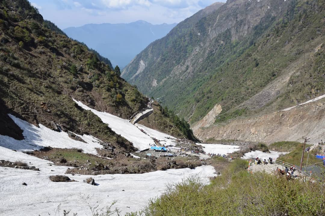 Breathtaking landscape of Kedarnath Valley, India, with hikers trekking through snowcapped mountains.