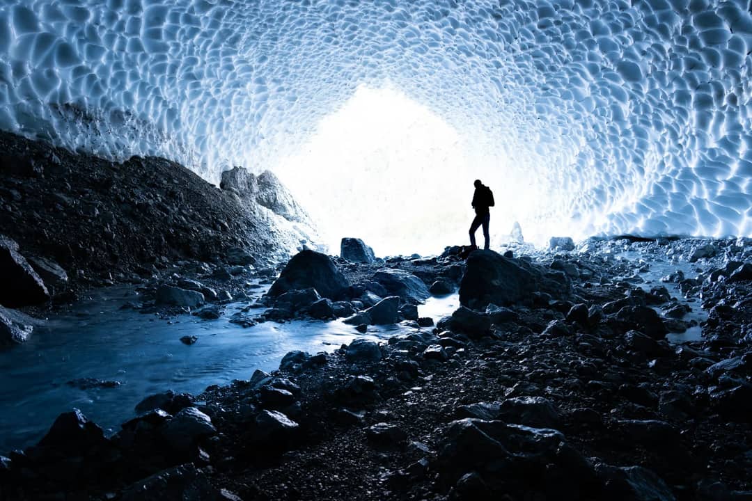 A figure standing at the mouth of an ice cave