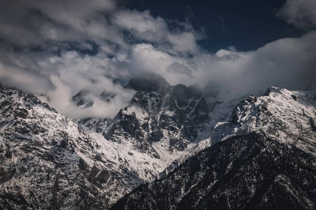 Stunning view of the snow-covered Himalayan mountains shrouded in clouds.