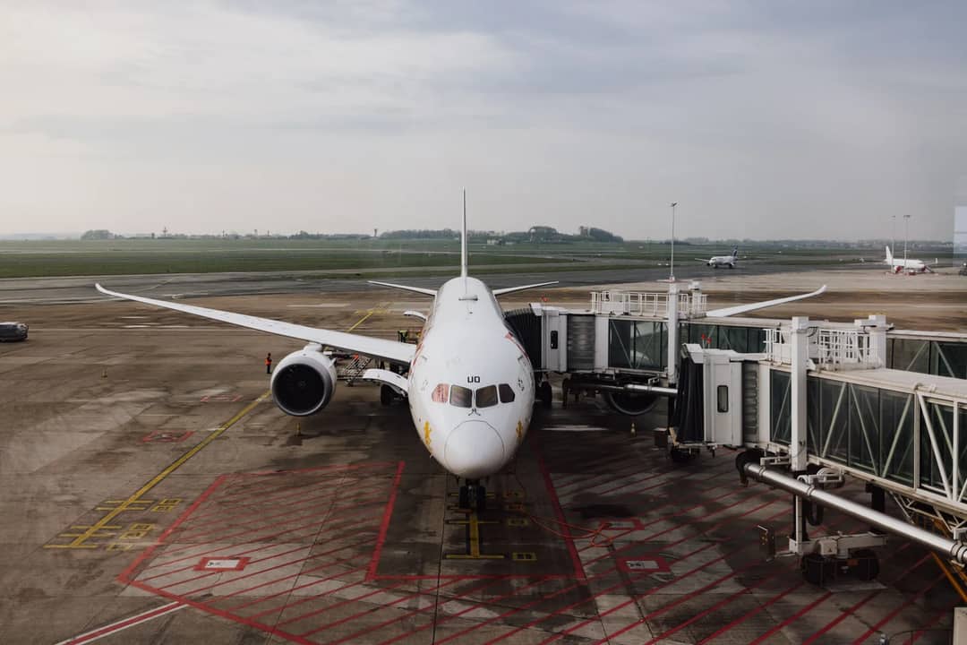 A modern jet airplane docked at an airport terminal gate, ready for boarding on a cloudy day.