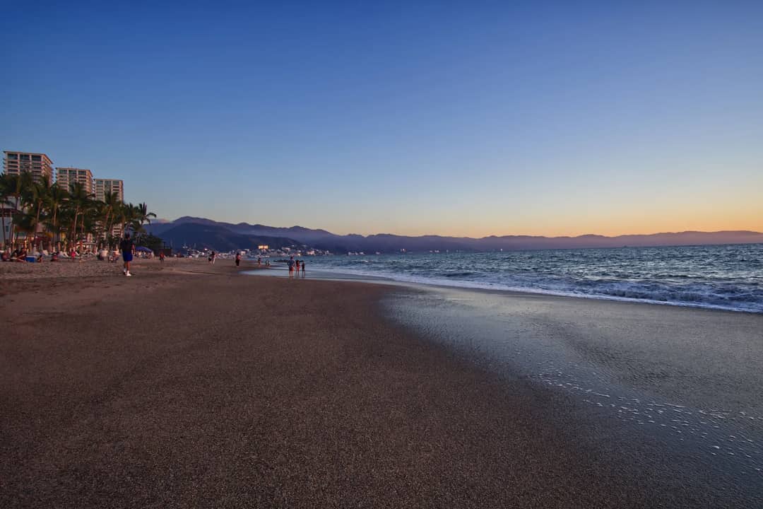 Beautiful sunset over a tropical beach in Puerto Vallarta, Mexico, with gentle waves and vibrant sky.
