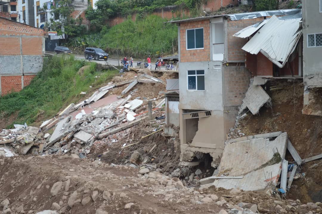 A residential building partially collapsed due to a natural disaster, showcasing severe structural damage.