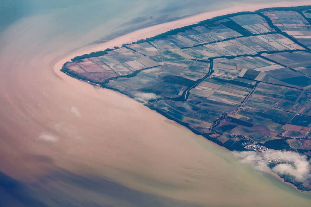 Stunning aerial shot capturing coastal farmland merging into the sea with distinct clarity.