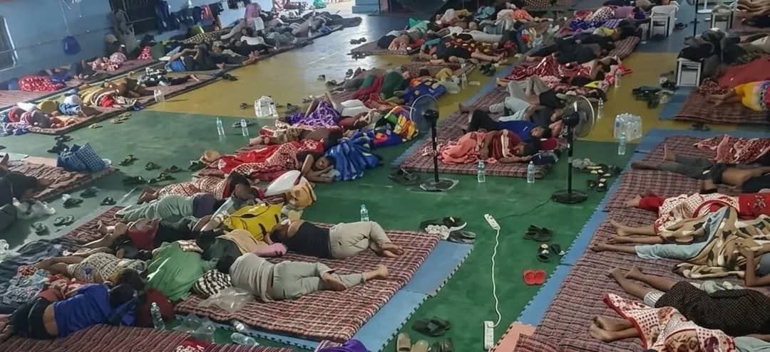 Displaced families asleep on mats laid out in rows across the floor of a covered hall in Trishuli, Nuwakot