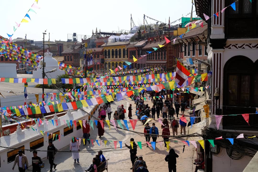 Colorful prayer flags adorn a busy street scene in Kathmandu, Nepal, showcasing urban life and cultural vibrancy.