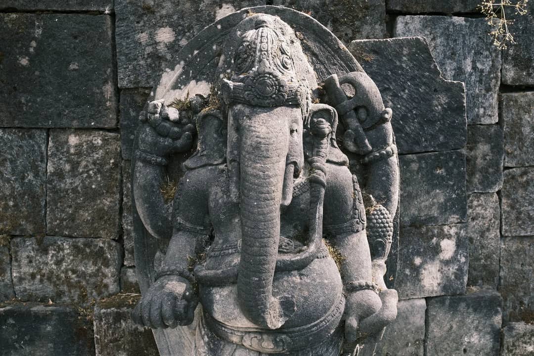 Intricate stone statue of Ganesha in an ancient temple, showcasing detailed craftsmanship.
