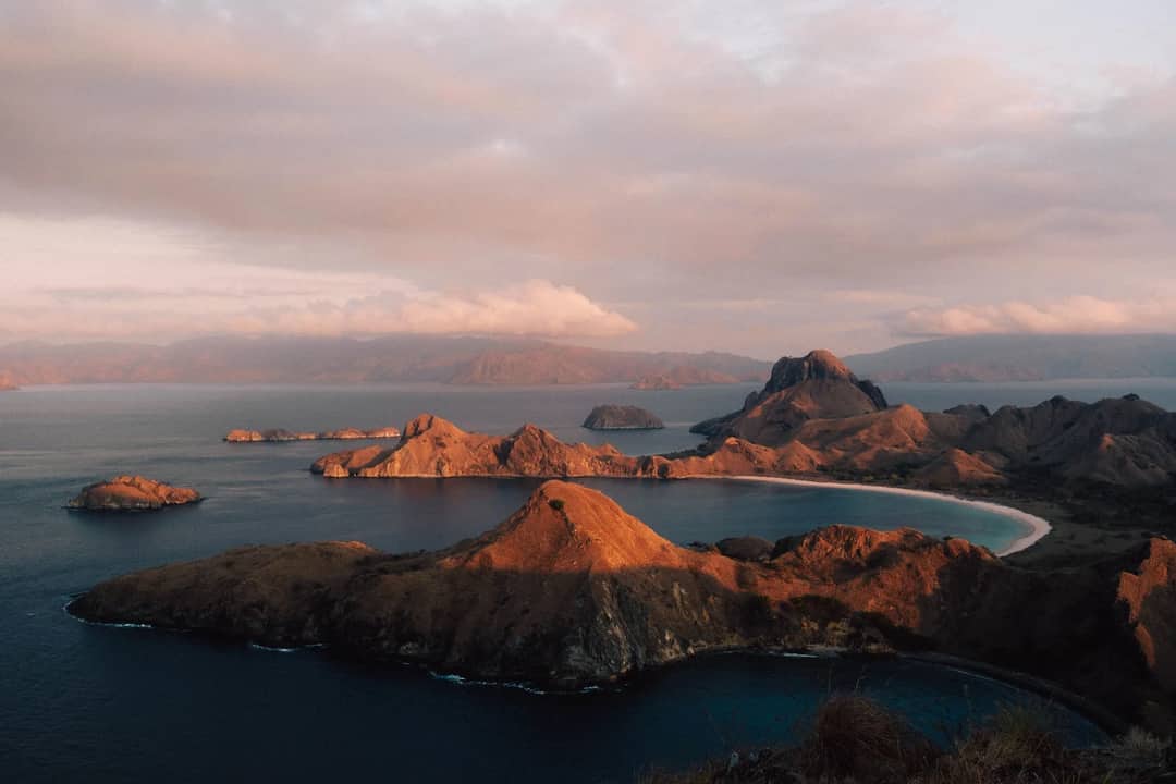 A breathtaking sunset view over the rugged coastline of Padar Island in Komodo National Park, Indonesia.