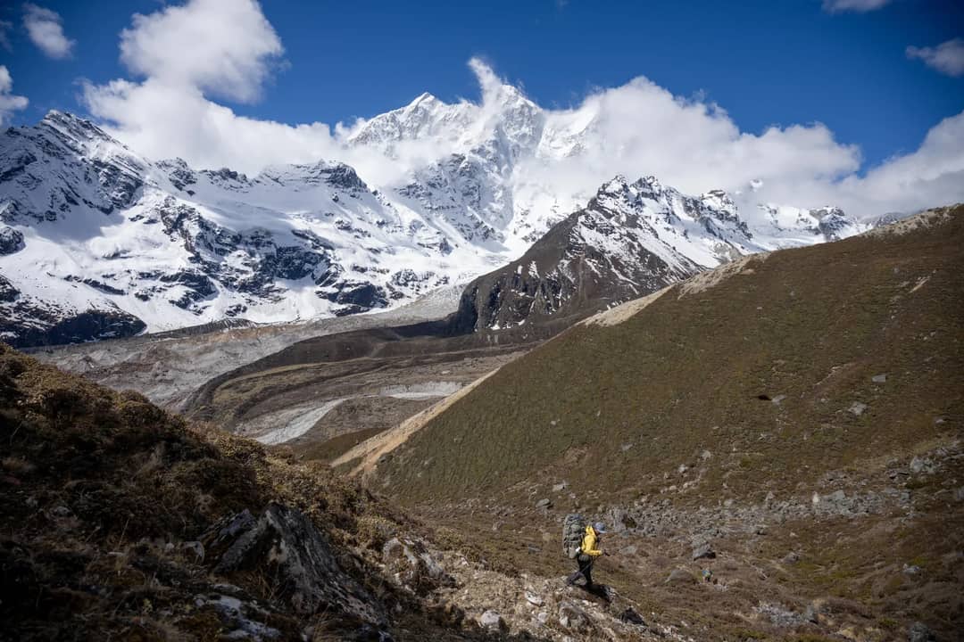 Backpacker trekking through remote snowcapped mountain landscape on a clear day.