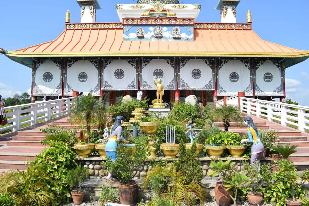 A vibrant Buddhist temple with garden decorations in Lumbini, highlighting religious architecture.