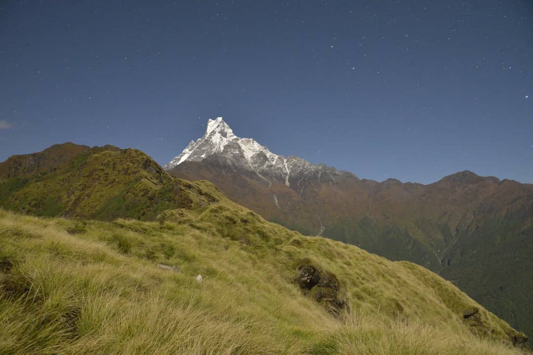 Breathtaking view of snow-capped mountains under a starry night sky, showcasing serene nature.