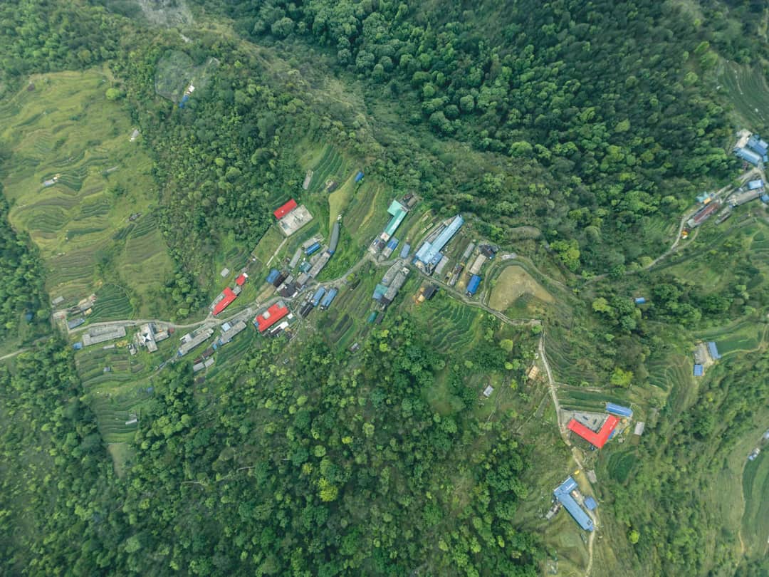 Stunning aerial shot of Ghandruk village amid terraced fields and greenery in Gandaki Province, Nepal.