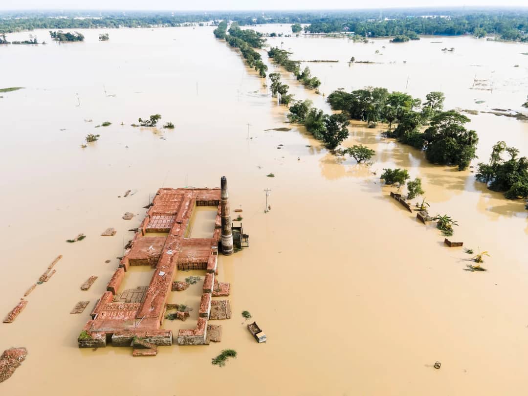 Aerial photo capturing a flooded landscape featuring a submerged brick kiln and surrounding greenery.