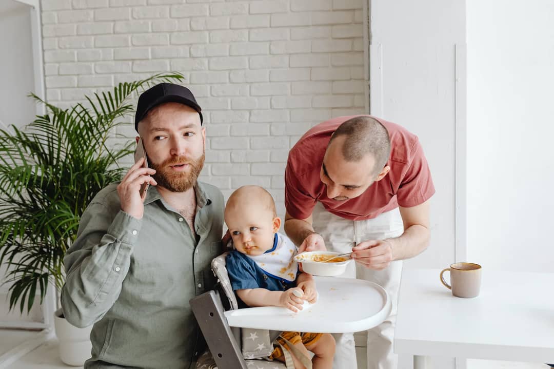 Two fathers enjoying breakfast with their toddler. Bright and heartfelt family moment.