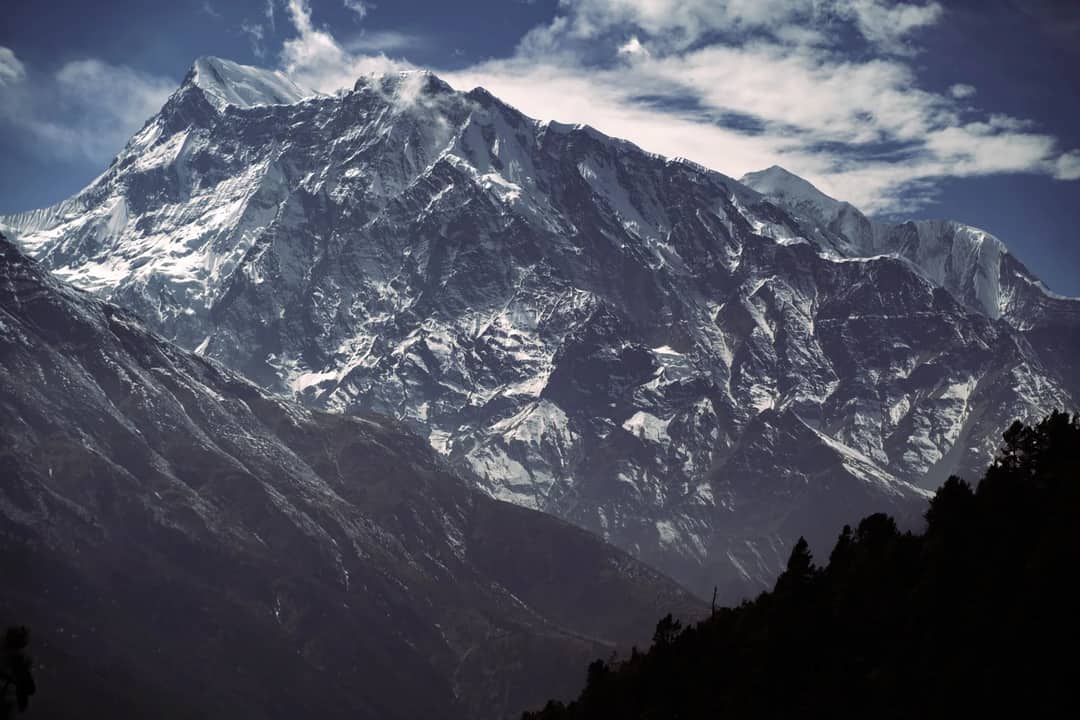 Stunning view of a snow-covered mountain range under a cloudy sky.