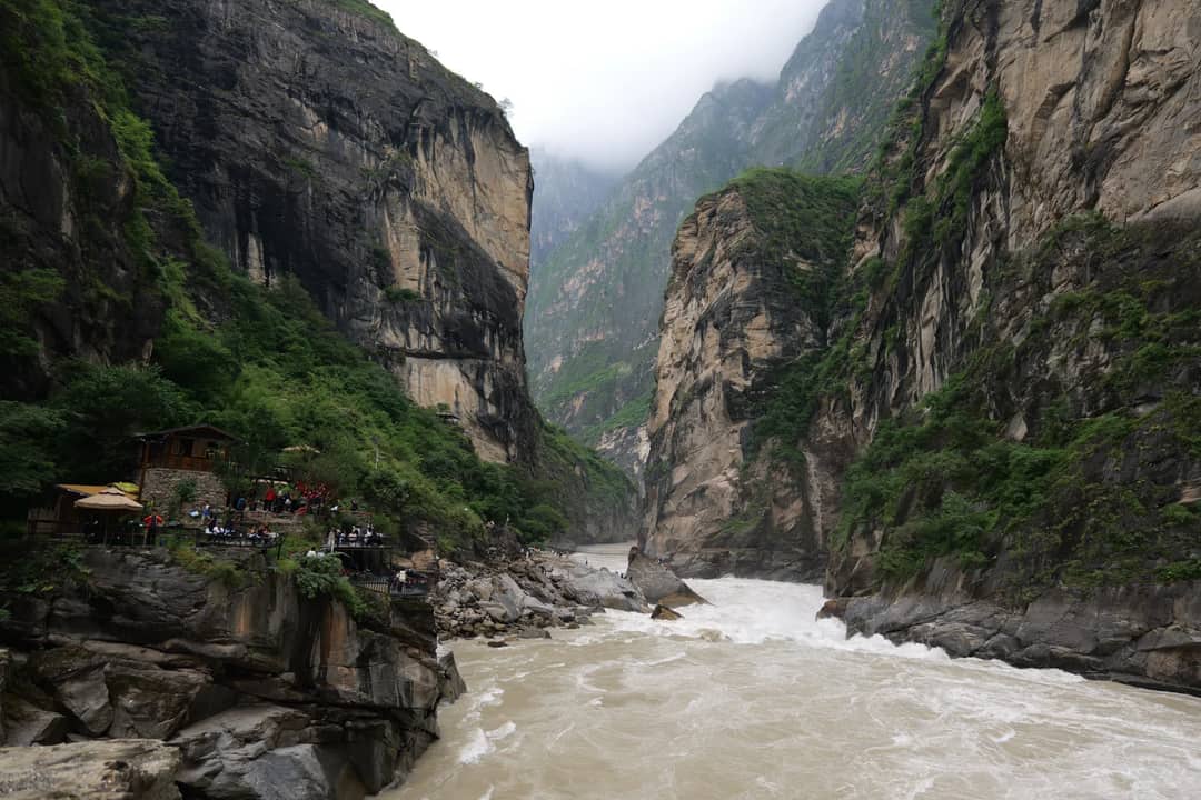 Scenic view of Tiger Leaping Gorge with rugged cliffs and roaring river in Yunnan, China.