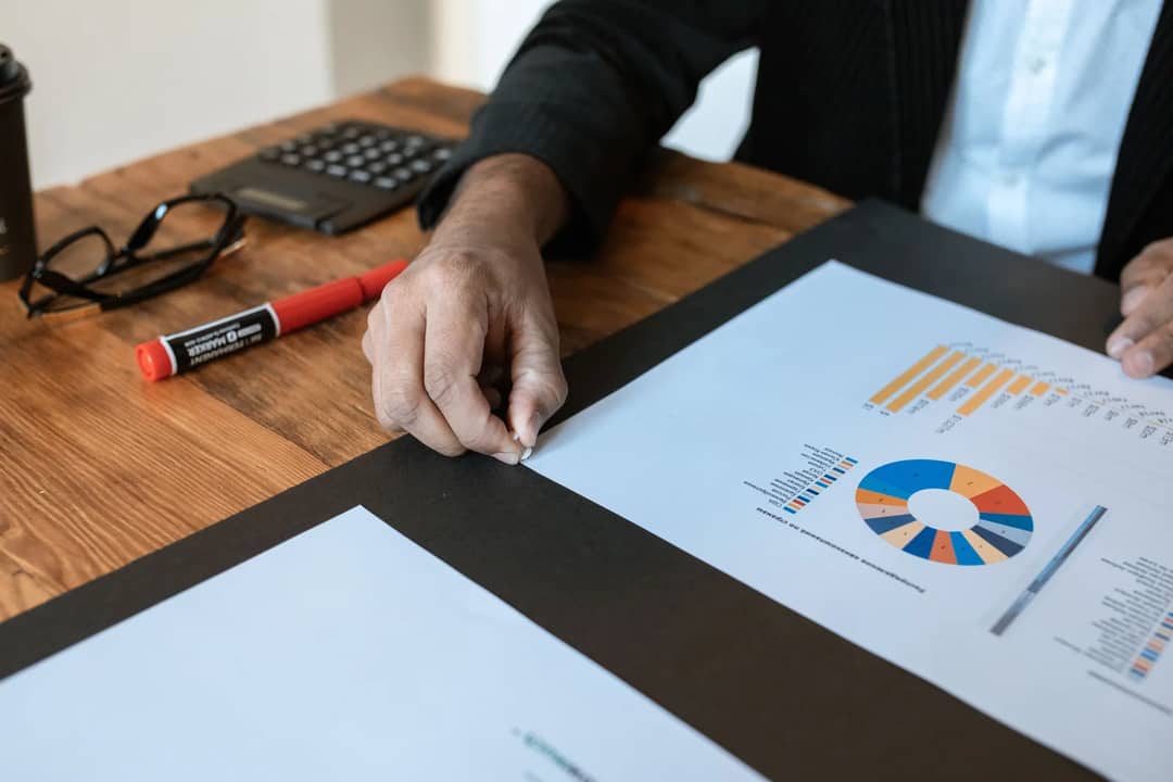 Close-up of a business setting with charts, documents, and a hand pointing.