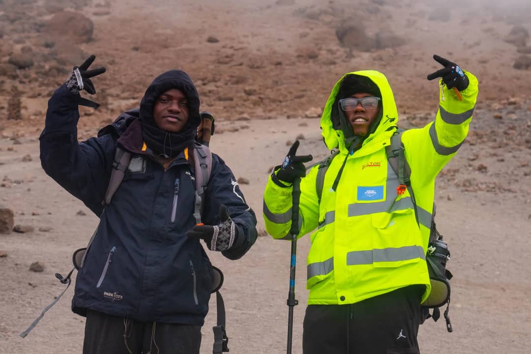 Two hikers pose on Mount Kilimanjaro, Tanzania, showcasing outdoor adventure.