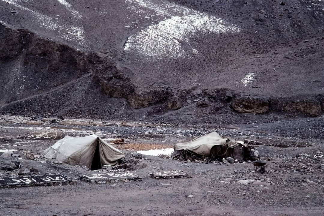 Tents pitched on rocky moraine below a mountain slope