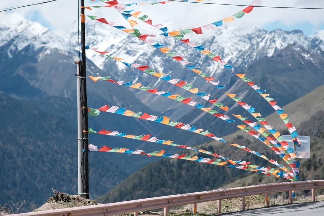 Prayer flags in the wind below snow peaks