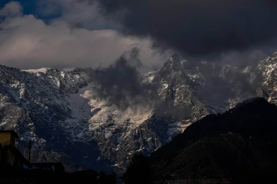 Storm cloud gathering over snow peaks