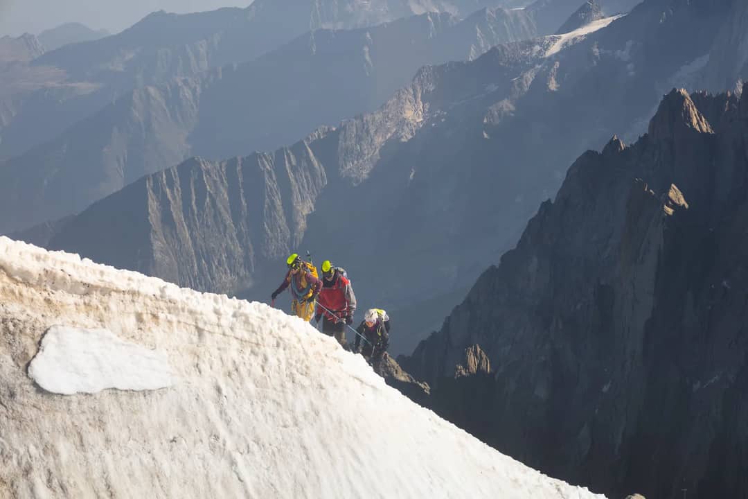 Roped climbers moving up a snow ridge