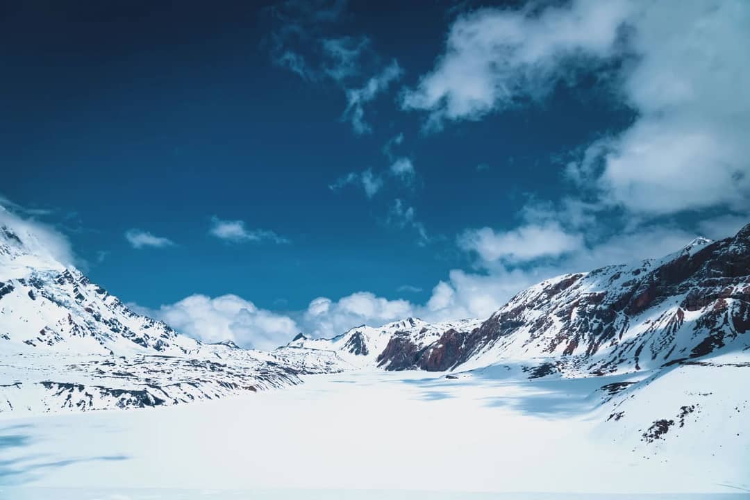 Snow slopes and a glacier below a Himalayan ridge