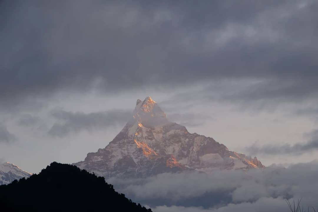 Stunning view of Machapuchare during sunrise with dramatic clouds in the Himalayas.