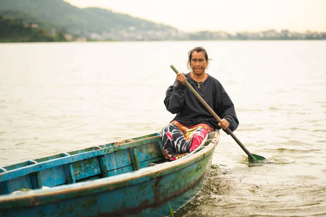 A woman paddles a colorful boat on Phewa Lake in Pokhara, Nepal.
