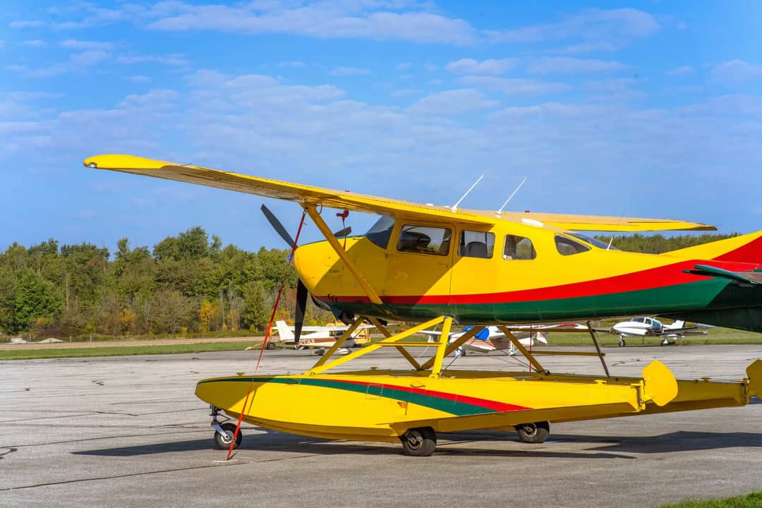 Bright yellow seaplane stationed outdoors at Stratford Airport in Ontario, Canada under clear blue skies.