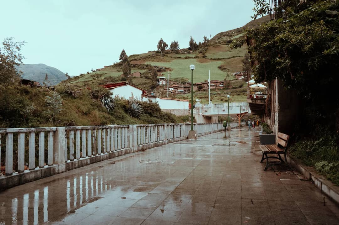 A tranquil pathway in Huaraz, Peru, featuring rustic architecture and lush landscapes after rain.