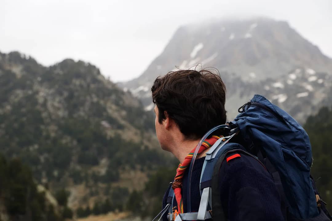 A man with a backpack hiking and enjoying mountainous scenery.
