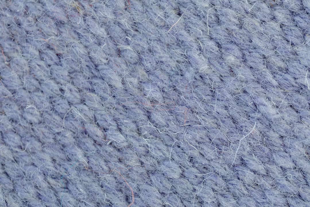 A knit fabric photographed close enough to show the loops of yarn — fibre type, not bacterial count, is what drove the odour ratings