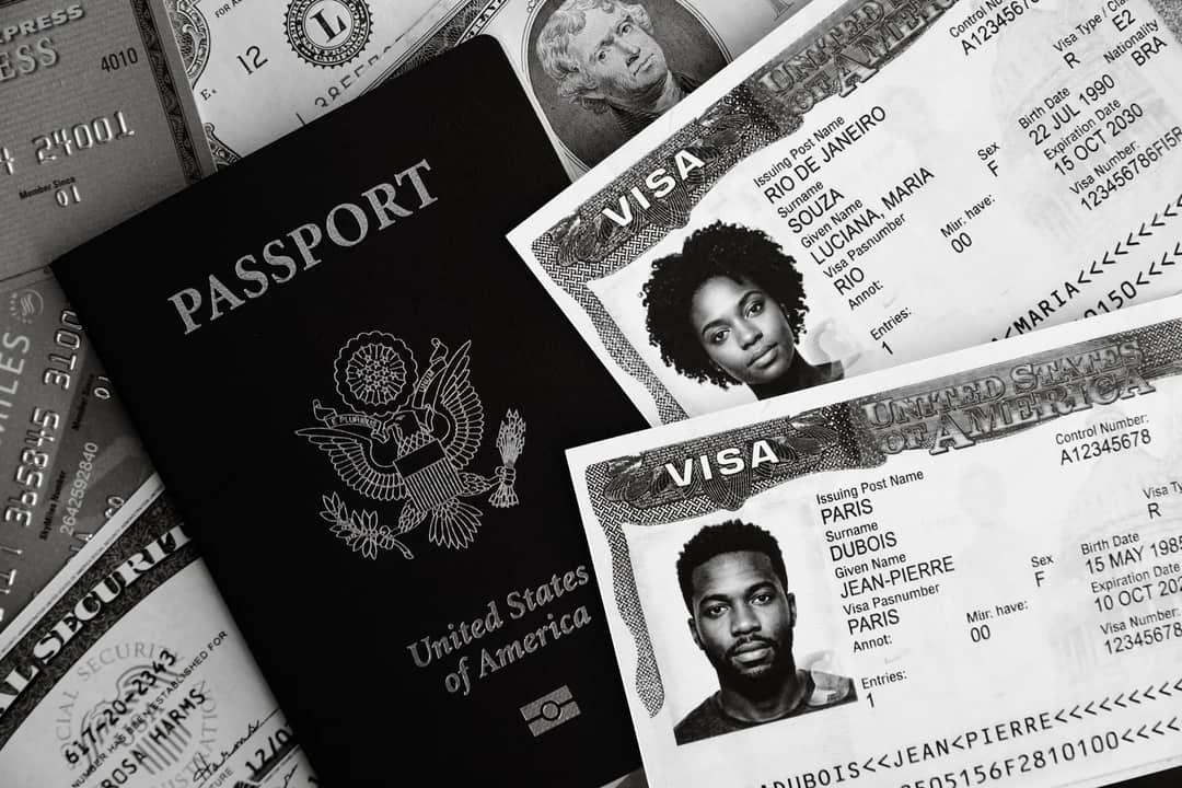 Monochrome photo of a US passport, visas, and currency, symbolizing travel and finance.