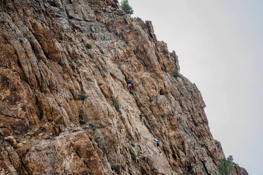 Adventurous rock climbers scaling a steep mountain cliff, showcasing courage and outdoor exploration.