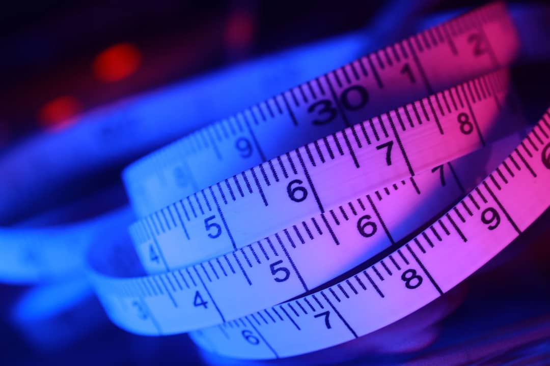 Abstract close-up of a measuring tape in vibrant blue and pink lighting.