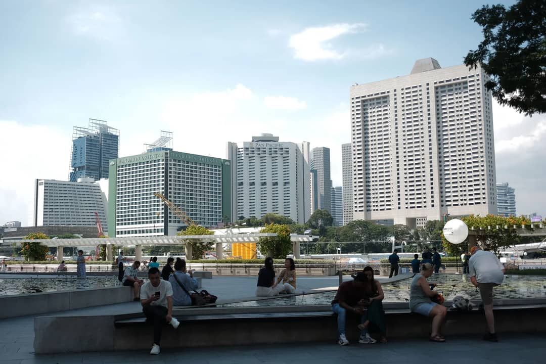 Discover the vibrant cityscape of Singapore with people enjoying the sunny day outdoors.