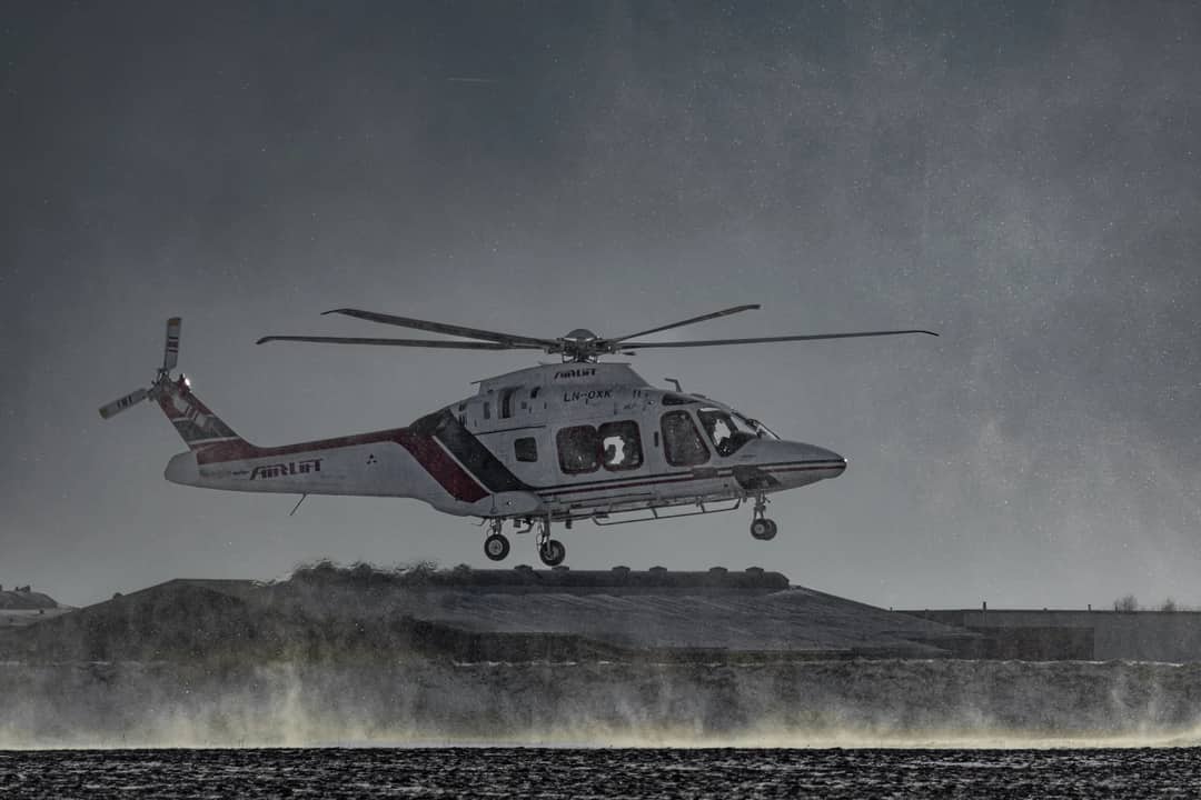 Air ambulance helicopter flying over a snowy terrain in winter conditions.